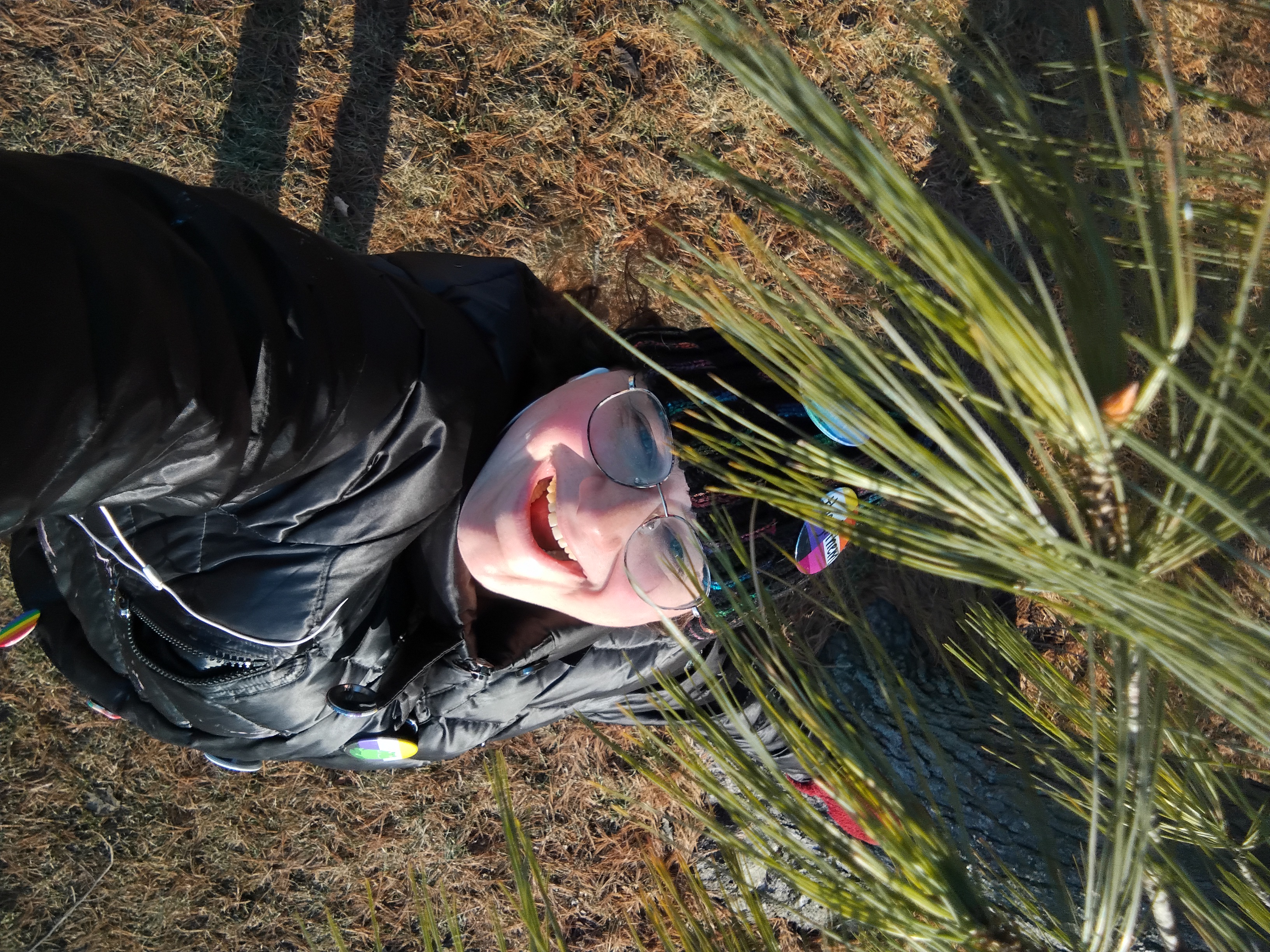 I'm smiling broadly with my mouth open, with some pine needles in the foreground.