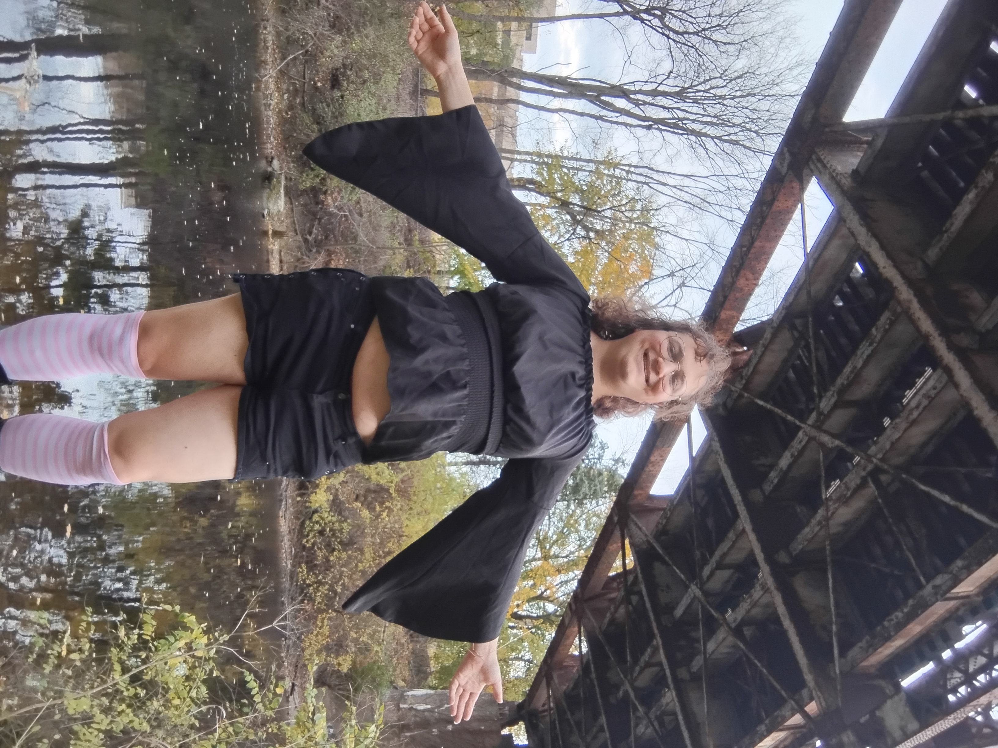 Me with arms spread and sleeves draped, underneath a bridge overpass, visible from thigh highs up.